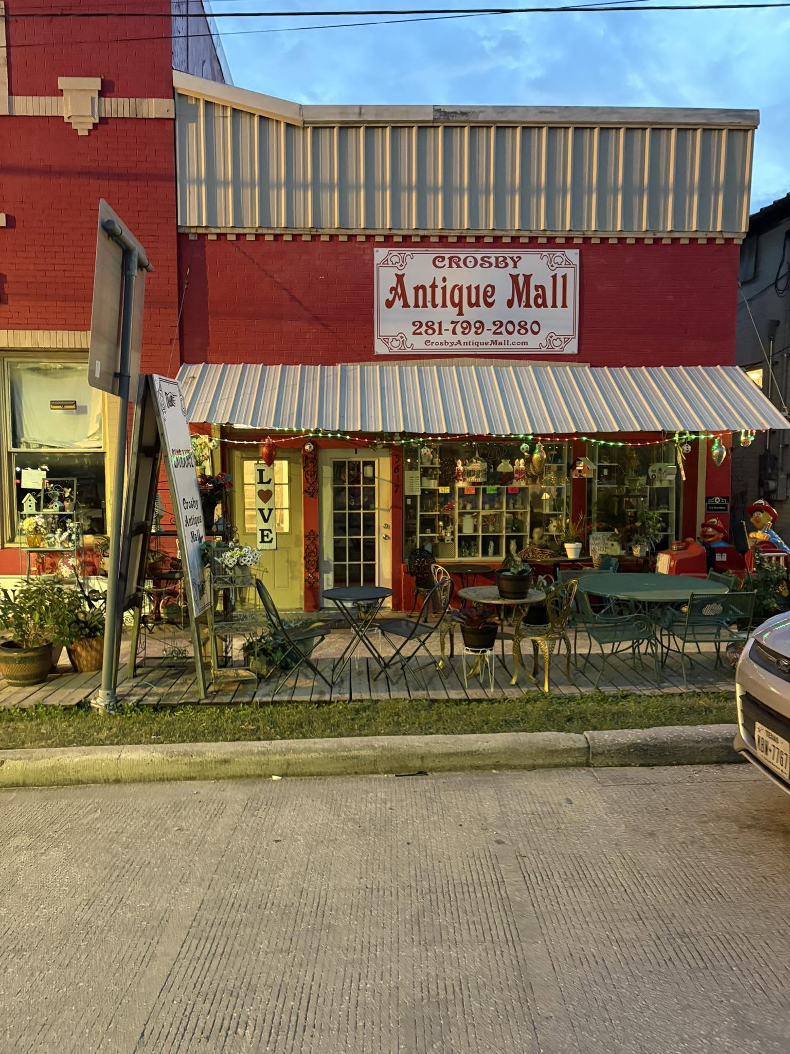 Crosby Antique Mall’s storefront, with its metal awning, display windows, and vintage furniture outside.